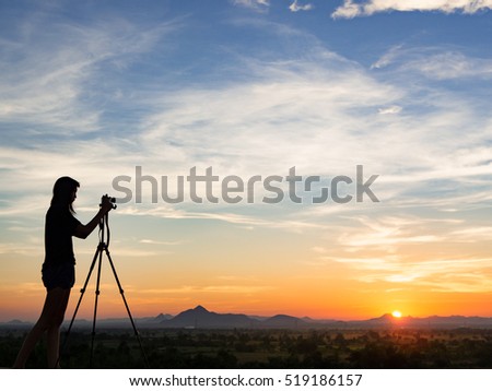 Silhouette of woman shooting with camera at sunset,mountain