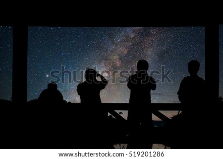 Silhouette of a photographers group who shoots the Landscape of Milky way over reservoir with mountain and deep forest at night sky