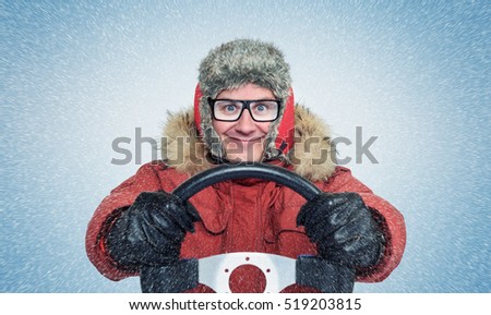 Happy Man in winter clothes with a steering wheel, snow blizzard. Concept car driver. Royalty-Free Stock Photo #519203815
