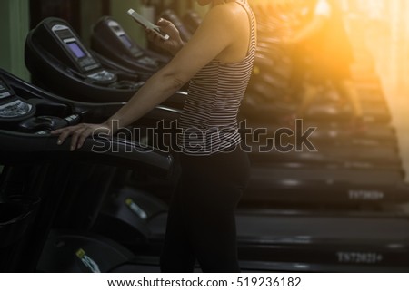 Woman Running On Treadmill At Gym and holding a phone  / soft focus picture