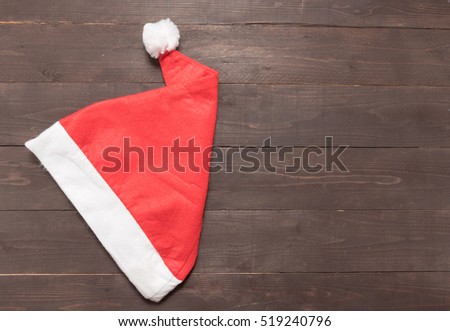 Red hat is on the wooden background with empty space for Christmas day.