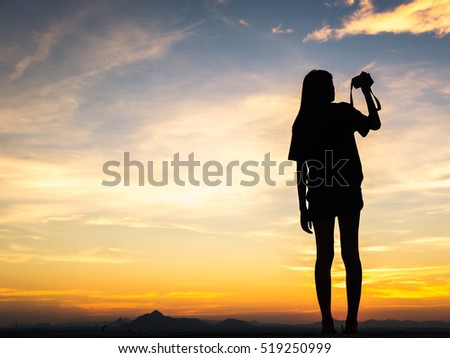 Girl photographer taking pictures with camera at sunset 