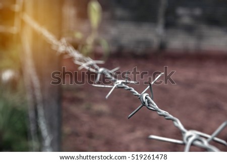 Barbed wire stretched along the fence with sunlight, safety concept