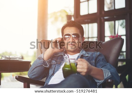 Young man with smartphone smiling relaxing at cafe.