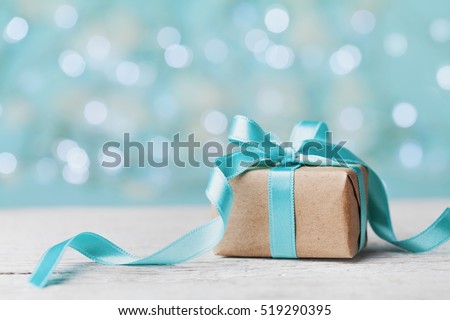 Christmas gift box against turquoise bokeh background. Holiday greeting card. Royalty-Free Stock Photo #519290395
