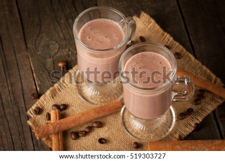 Photo of fresh Made Chocolate Banana Smoothie on a wooden table with coffee and spices. Selective focus. Milkshake. Protein diet. Healthy food and hot drink concept. Drink, coffee