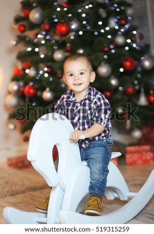 A little boy sitting under the Christmas tree with toys and gifts for the New Year or Christmas