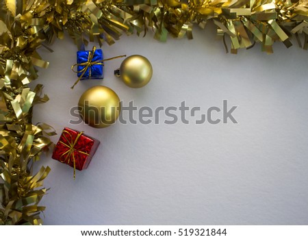Christmas ornament flat composition with white board. Golden ribbon with fir tree ornament. Gold fir tree balls. Red and blue wrapped gifts. Festive photo background with Christmas frame and presents