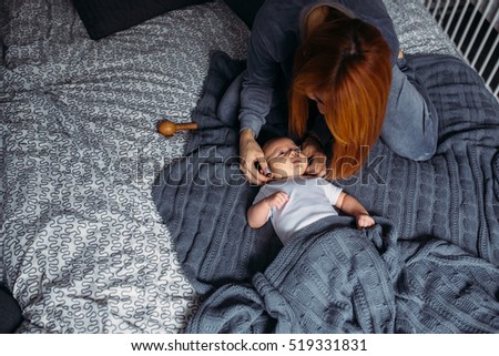 Portrait of a mother with her baby in bedroom at home