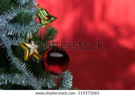 Close-up of christmas tree decorated with ornaments in rich shiny red background - with copyspace