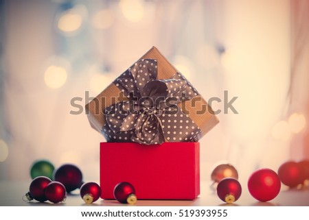Christmas gift and baubles around it on fairy lights background