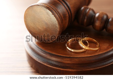 Golden wedding rings with judge gavel, closeup Royalty-Free Stock Photo #519394582