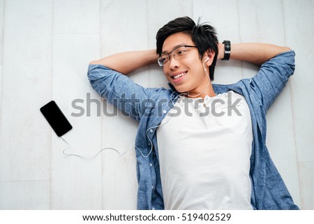 Young asian man in shirt on the floor. with phone. looking away