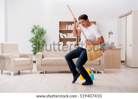 Man cleaning home with broom Royalty-Free Stock Photo #519407410