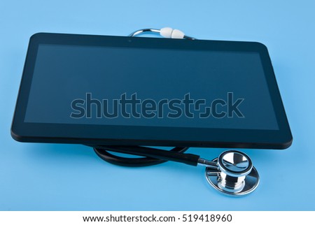 stethoscope and tablet on blue background closeup