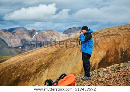 man hiker photographer taking picture on the rhyolite mountains background in Iceland