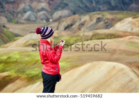 woman hiker photographer taking picture on the rhyolite mountains background in Iceland