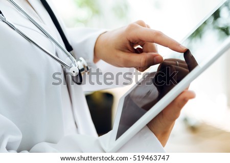 Portrait of female doctor using her digital tablet in the office. Royalty-Free Stock Photo #519463747
