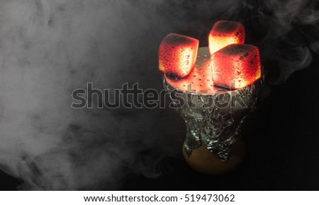 Shisha bowl with craft tobacco and red coil with hookah smoke background. Royalty-Free Stock Photo #519473062