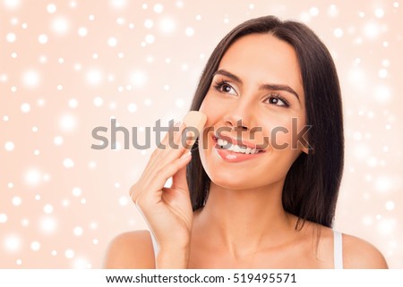 Portrait of pretty woman evening her skin tone with sponge. Xmas concept