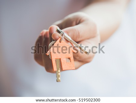 Female hand holding house key,real estate agent. Royalty-Free Stock Photo #519502300
