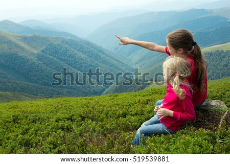 two girls sitting on a grass and  looking at the mountains
 Royalty-Free Stock Photo #519539881