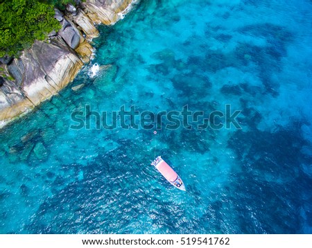 Aerial view of a tropical island with blue clear water, coral reef and lush greenery on a granite stones. . Similan Islands, Thailand. Speedboats on a coral reef from above.