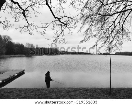 One fishing man hunting on the pond or lake. Black and white photo. Nice hobby 