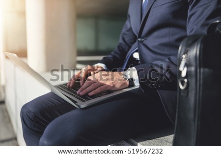 Man wearing suit works oh his notebook. Horizontal outdoors shot Royalty-Free Stock Photo #519567232