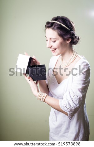 Joyful happy woman holding gift box over light background. Closeup portrait