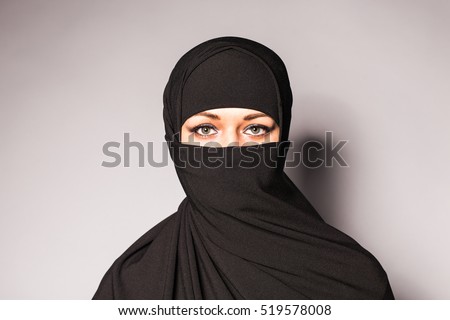Portrait of an arabic young woman with her beautiful blue eyes in traditional islamic cloth niqab. Royalty-Free Stock Photo #519578008