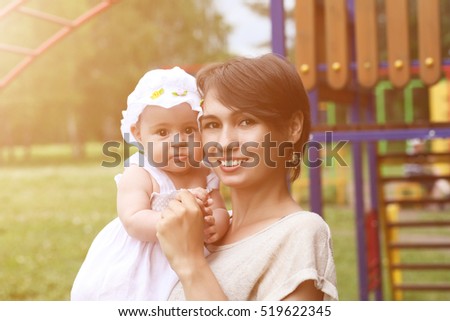 Happy young mother walks in the park with her little daughter. Toned