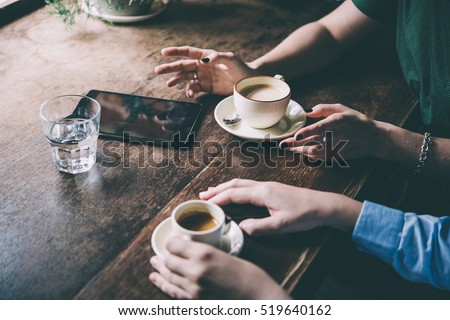 Two women discussing business projects in a cafe while having coffee. Toned picture