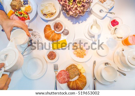 Beautiful English Afternoon Breakfast Ceremony with Desserts and Snacks in Luxury Berlin Hotel, Man's Hands taking Teapot, Top View, Toned Image