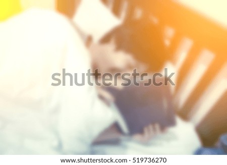 blur background of man smile and play tablet with retro filter on bed