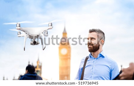 Hovering drone taking pictures of businessman in London