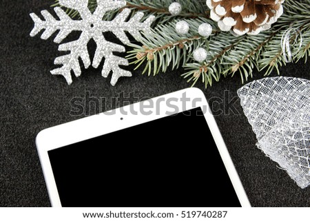Tablet with christmas decoration, silver ribbon, branch of pane, silver snowflake, and snow cone 