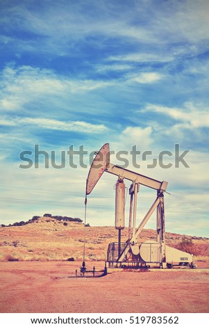 Vintage toned picture of an oil pump, old industrial equipment on arid soil.