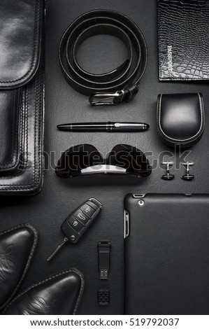 Man accessories in business style, briefcase, gadgets, shoes, clothes and other luxury businessman attributes on leather black background, fashion industry, top view  Royalty-Free Stock Photo #519792037