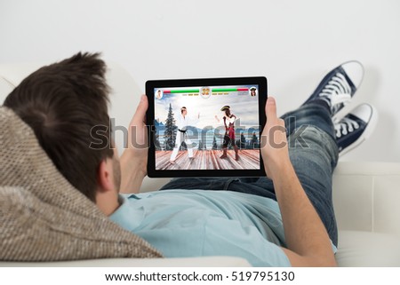 High Angle View Of Man Playing Videogame On Digital Tablet At Home