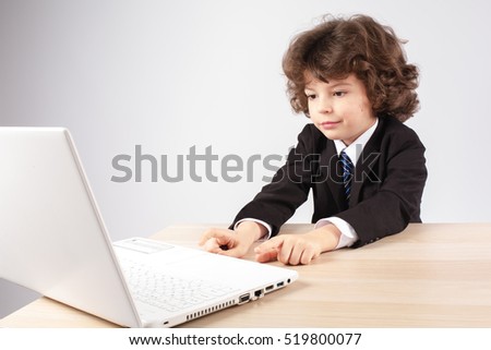 Little curly businessman typing on a laptop. Gray background.
