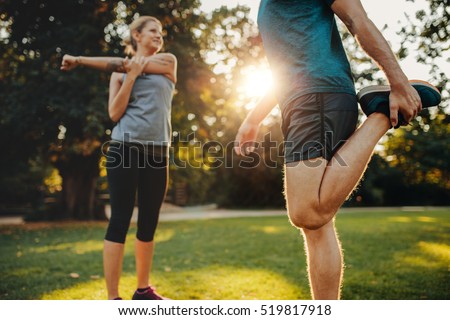 Shot of young man and woman stretching in the park. Young couple warming up in morning. Royalty-Free Stock Photo #519817918
