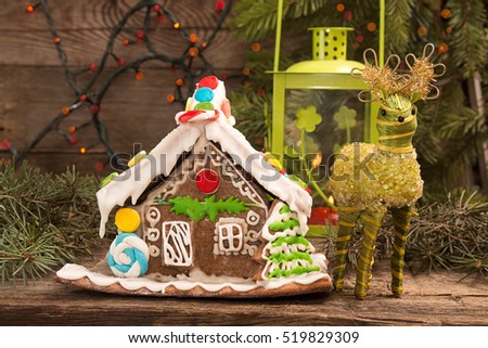 Gingerbread house. European Christmas holiday traditions. Christmas gingerbread house, lantern, deer and holiday decorations on old wooden table. Christmas holiday sweets.