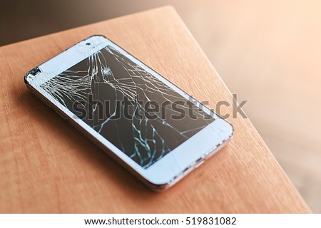 Smartphone with broken screen on the wooden table