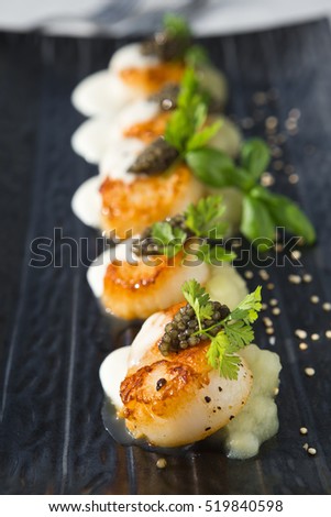 Delicious pan seared organic scallops, served with celery puree, caviar, parsley and white wine cream sauce. Presented professionally and shot with a shallow depth of field.