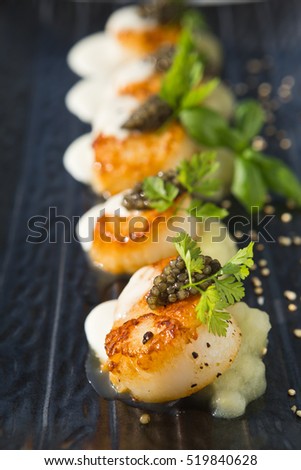 Delicious pan seared organic scallops, served with celery puree, caviar, parsley and white wine cream sauce. Presented professionally and shot with a shallow depth of field.