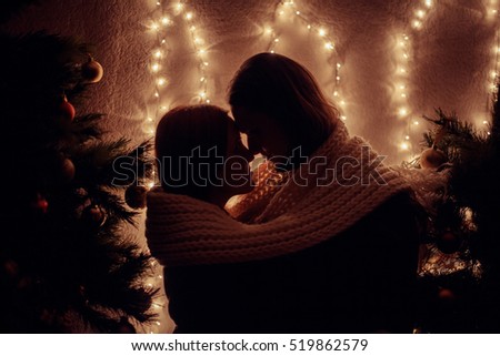 Young couple kissing near Christmas tree. Low key. Silhouette