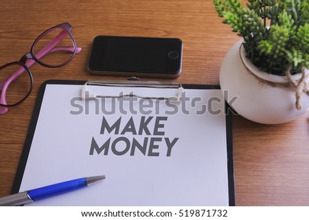 MAKE MONEY word written on paper with glass, smartphone and green plant, copyspace area