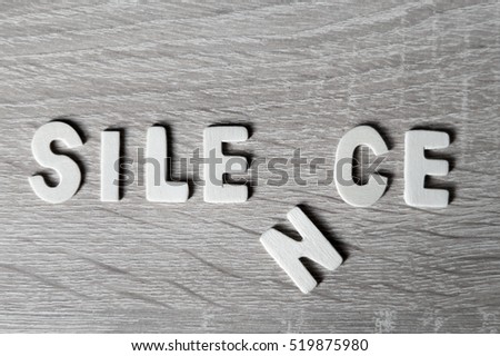 Background. Letters on wooden table. "Silence".