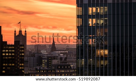London Sunset. A view over the UK capital city with the flag topped Victoria Tower, Palace of Westminster, contrasting against the skyline.